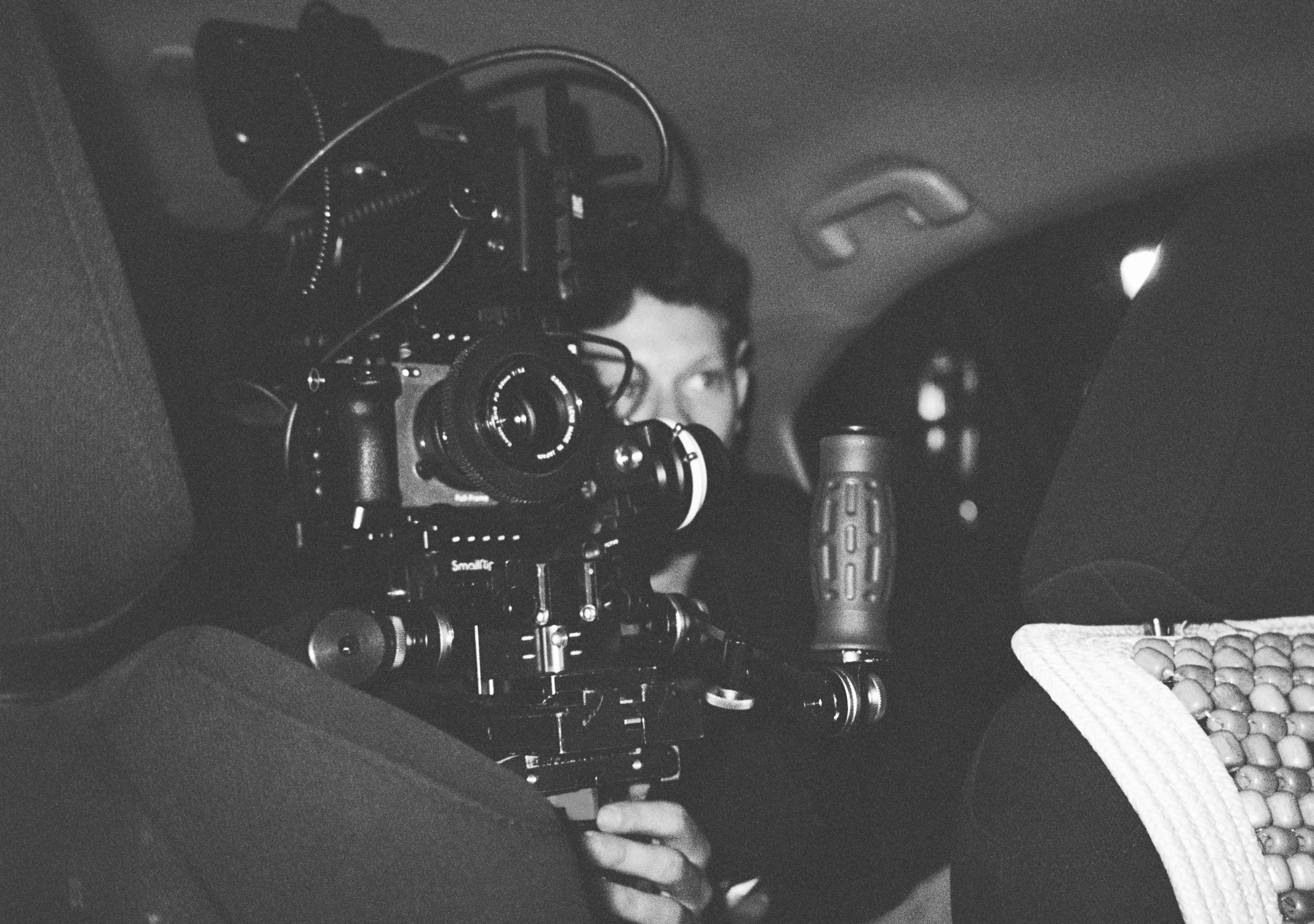 Operador de cámara grabando dentro de un coche, en blanco y negro